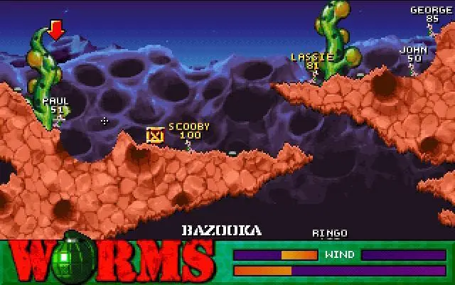 A screenshot of the original Worms. A group of worms named after the Beatles are locked in a duel to the death against a group of worms named after fictional dogs. Paul is currently firing a bazooka at Scooby.
